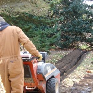 A trench is made to install a French swale which helps alleviate standing water without having a visible swale in your yard.