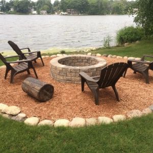 A scenic space is created beside Tichigan Lake in Waterford, WI with Unilock Stackstone fire pit, crushed granite and small boulder edge.