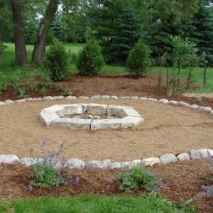 Large slabs of stone create a natural looking fire pit surrounded with decorative stone and small boulder edge.