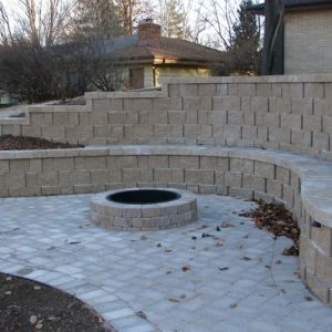 A nook created by the curving retaining wall is used for a paver patio with fire pit. Project by Dresen Landscape Contractors LLC, Racine, WI,