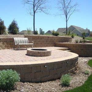 County Materials paver patio with fire pit is installed between tiered block retaining walls in Mount Pleasant.