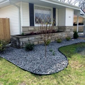 After image: Front of home s updated with new shrubs and grey sparkle granite planting bed.