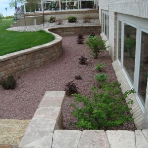 Retaining wall with steps made of Unilock Estate wall blocks installed to create space around egress windows for home along Lake Michigan in Kenosha, WI