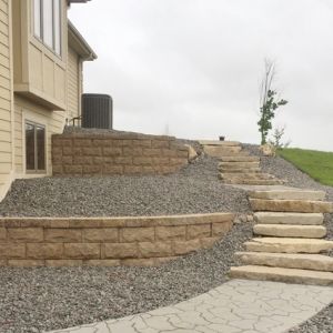 Retaining Walls made of Rockwood Classic 8 Chiseled Face retaining wall block with lily pad steps connect front of home with lower walkout in Raymond, WI.