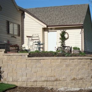 Steep slopes next to a residence are corrected by installing retaining walls in Racine, WI. Wash out of soil around the foundation will be prevented.
