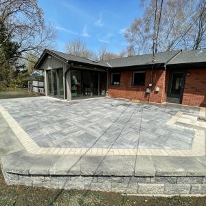 County Materials Grand Discover paver patio (majestic color) with Tribute block retaining wall (silvertone color).
