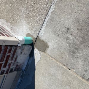 Downspout connected to SDR-35 runs under concrete sidewalk to street to direct water off sidewalk.