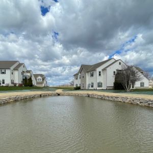 Rustic gold outcropping stone retaining walls installed along pond shorelines at Villas of Racine condominiums in Mount Pleasant, WI