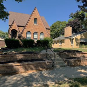 Two-tiered retaining wall installed along city sidewalk to eliminate steep mowing hill in Bay View (Milwaukee, WI). County Materials Tribute block in canyon brown color.