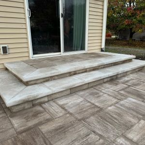 Patio door steps installed in Mount Pleasant, WI using County Materials Smooth Tribute block (enlighten color) with Prestige coping (sea salt color).